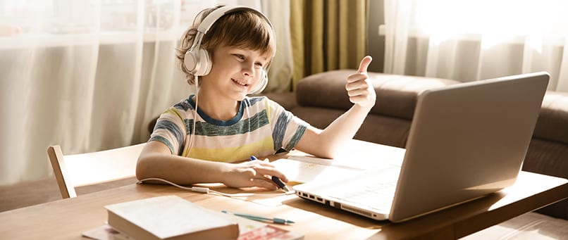 Chlapec so slúchadlami pri notebooku počas online vyučovania